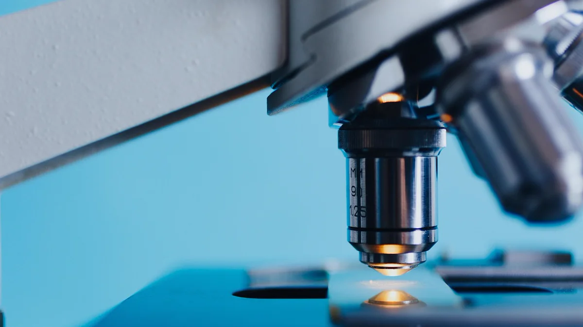 Microscópio óptico vintage em ambiente de laboratório, ilustrando o trabalho óptico de Royal Rife no início do século XX.